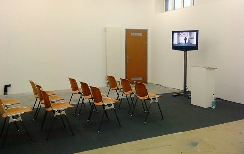 Büro für Leerstand, Installationsansicht «On Tour» (Vortragsraum mit TV,
Pult, Stühlen und Video), 2010